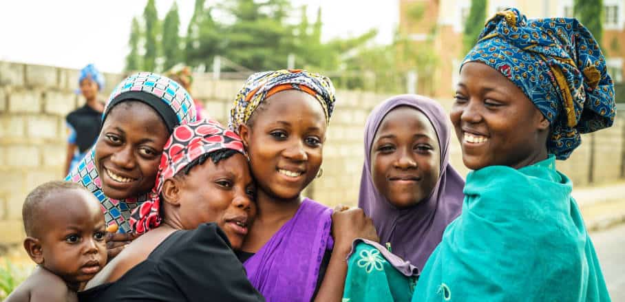 A group of young Black women laughing and hugging each other in the street.