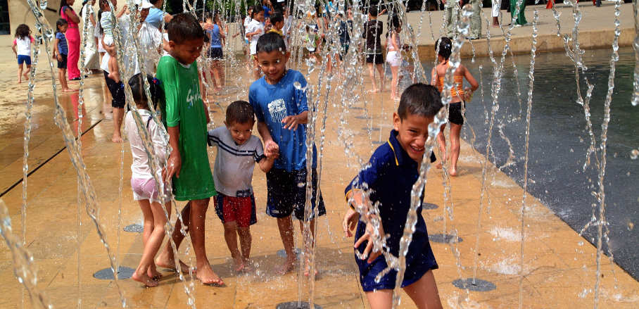 Children enjoy the water columns in a public park.